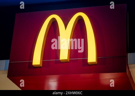 Detaillierte Ansicht des hellgelben McDonalds-Emblems mit den berühmten goldenen Bögen vor einem leuchtend roten Hintergrund. 13. Mai 2024 Sanya China Stockfoto