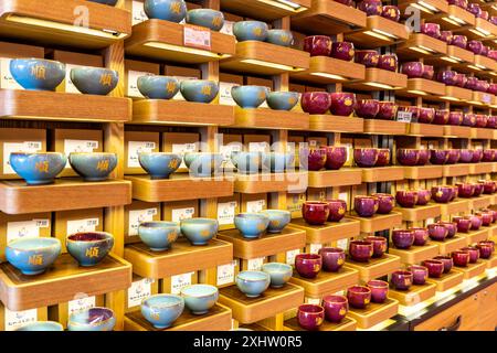 Sanya, China - 17. Mai 2024: Keramikbecher. Wunderschöne Teetassen für die Teezeremonie im Regal im Laden. Stockfoto