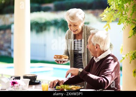 Seniorenpaar, Garten und Essen zusammen zu Hause, Binden und Frühstück für Essen und Kaffee. Draußen, glückliche oder verheiratete Leute im Haus zum Brunch in Stockfoto
