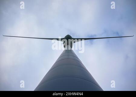 Dieses Bild zeigt eine Nahaufnahme einer modernen Windturbine mit niedrigem Winkel vor einem klaren blauen Himmel. Das schlanke, aerodynamische Design des b Stockfoto