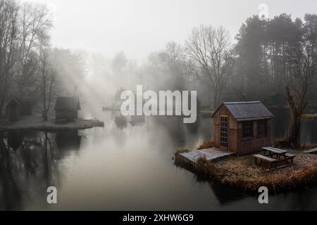 Szodliget, Ungarn - aus der Vogelperspektive eine traumhafte Winterszene am Szodliget Angelsee mit Fischerhütten und starkem Nebel an einem kalten Wintermorgen Stockfoto