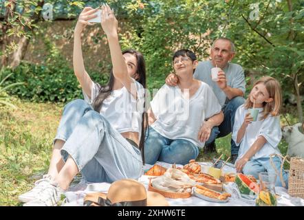 Familie macht Selfie während des Picknicks. Ein Mädchen macht ein Selfie mit ihrer Familie auf ein Picknick Stockfoto