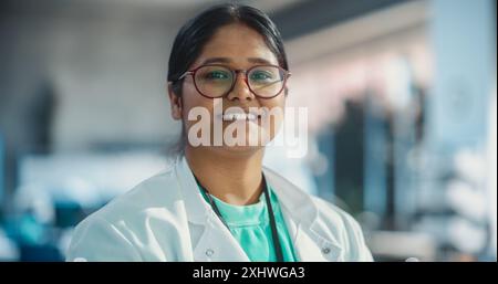 Portrait Nahaufnahme einer jungen indischen Spezialistin mit Labormantel und Brille lächelnd. Professionelle und erfolgreiche Frau, die als Ingenieurin arbeitet, Science Studentin in University Laboratory Posing Stockfoto