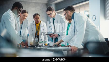 Internationale Fertigungsleiter diskutieren über Daten, die in der Produktanalyse mit Laptop- und Tablet-Computern gesammelt wurden. Gruppe von Young Professional Specialists: Brainstorming, Problemlösung Stockfoto