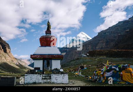 Eine ruhige Szene einer tibetischen Stupa mit Gebetsfahnen vor dem Hintergrund eines majestätischen schneebedeckten Berges und eines hellblauen Himmels Stockfoto