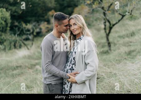 Wunderschönes Paar einer schwangeren Frau und ihr Mann stehen im Garten. Stockfoto