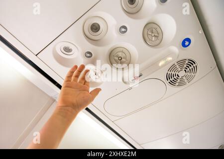 Child adjusting the overhead panel on an airplane. Stockfoto