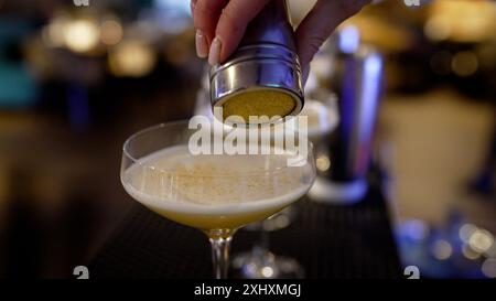 Nahaufnahme der Hände eines Barkepers, der Cocktails zubereitet. Hände einer Barkeeperin, die einen Cocktail aus der Nähe zubereitet. Stockfoto