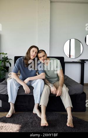 Ein junges schwules Paar entspannt sich auf einem Bett im Schlafzimmer, ihre Intimität und Liebe spürbar. Stockfoto