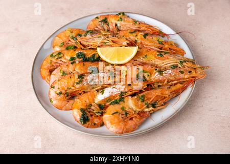 In Butter mit Knoblauch und Petersilie gebratene Langoustinen. Serviert mit einer Zitronenscheibe. Traditionelle mediterrane Küche. Eine beliebte Vorspeise in Restaurants Stockfoto