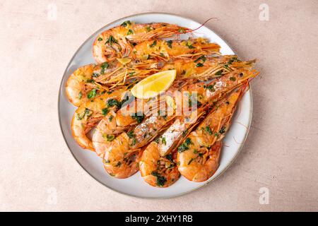 In Butter mit Knoblauch und Petersilie gebratene Langoustinen. Serviert mit einer Zitronenscheibe. Traditionelle mediterrane Küche. Eine beliebte Vorspeise in Restaurants Stockfoto