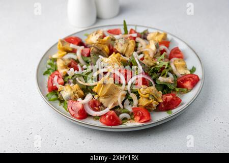 Warmer Salat mit rapan (Schnecken), Tomaten, Zwiebeln, Blattgemüse und Olivenöl. Traditioneller Salat mit Meeresfrüchten. Nahaufnahme, selektiver Fokus. Stockfoto