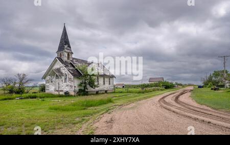 Alte verlassene Holzkirche neben einer Schotterstraße im Dorf der Kriegszeit, Saskatchewan, Kanada Stockfoto