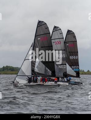 Die Segelboote, die an einem bewölkten Tag mit Matrosen in farbenfroher Ausrüstung an einem Rennen teilnehmen. Stockfoto