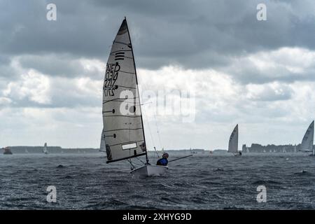 Ein Segelboot auf einem abgehackten Meer unter bewölktem Himmel mit anderen Booten im Hintergrund Stockfoto