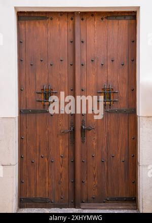 Eine alte Holztür mit geschmiedeten Griffen und geschmiedeten Scharnieren, kleine Sichtfenster mit Gittern. Mallorca, Majorka Spanien Stockfoto