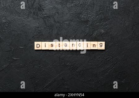 Distanzierungsswort auf Holzblock geschrieben. Distanzierungstext auf Zementtisch für Ihr Design, Konzept. Stockfoto