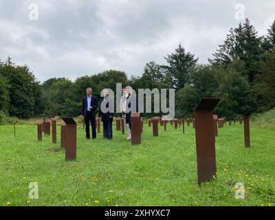 16. Juli 2024, Schleswig-Holstein, Schwesing: Burkhard Jansen, Leiter der Kulturabteilung des Landkreises Nordfriesland, Landrat Florian Lorenzen, Wilfried Christiansen, stellvertretender Vorsitzender der KZ-Gedenkstätte Freunde Husum-Schwesing, und Friedemann Magaard, Vorsitzender der Freunde (von links nach rechts), stehen auf einem Stelenfeld auf dem Gelände des ehemaligen Vorlagers. Die Gefangenen mussten von Ende September 1944 bis Ende Dezember 1944 13 Wochen lang Panzerabwehrgräben ausheben. Mehr als 300 von ihnen starben. Das 13-Wochen-Projekt wurde zur Feier gestartet Stockfoto