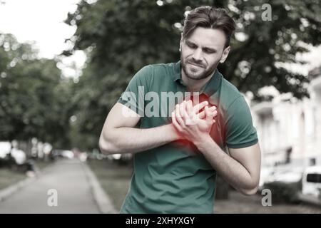 Herzinfarkt. Ein Mann leidet unter Schmerzen und drückt draußen die Hände auf die Brust Stockfoto