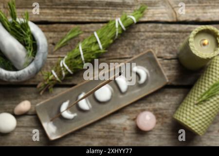 Flache Lagenkomposition mit Räucherstäbchen schwelend in Halter auf Holztisch Stockfoto