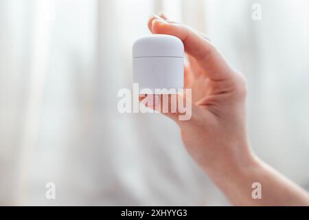 Nahaufnahme des Nachahmens einer Flasche kosmetischer Mittel in der Hand einer jungen Frau. Weibliche Hand mit gepflegter Maniküre hält ein Glas Creme. Kosmetologie und Dermatolo Stockfoto