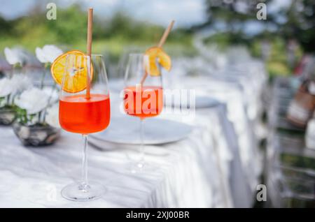 Nahaufnahme von Gläsern mit aperol und Orangenscheiben auf einem Tisch mit weißer Tischdecke. Köstliche alkoholische Getränke bei einem festlichen Mittagessen im Garten. Dez Stockfoto