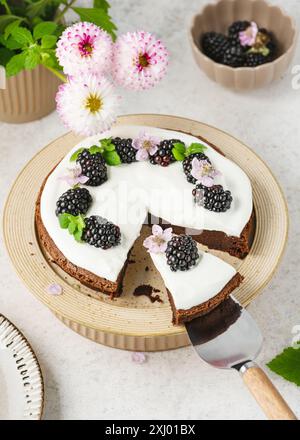 Blick von oben. Stück hausgemachter Schokoladenkuchen mit Vanillecreme, verziert mit brombeere, Blüte und Zitronenmelisse auf einer Kuchenlöffel. Stockfoto