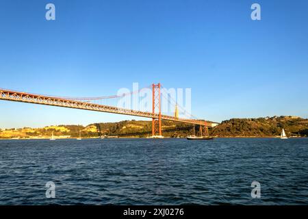 Das Heiligtum Christi des Königs (Portugiesisch: Santuário de Cristo Rei) und die Brücke 25 de Abril bei Sonnenuntergang vom Tejo aus gesehen, Lissabon Stockfoto