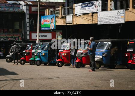 Reihe farbenfroher Auto-Rikschas, die vor einem Marktgebiet in Haputale, Sri Lanka, geparkt sind. Stockfoto