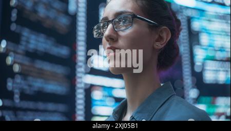Nahaufnahme Porträt einer Frau, die am Computer arbeitet, Zeilen der Code-Sprache reflektiert auf ihrer Brille von großen Bildschirmen. Programmiererin Entwickelt Neue Software, Codierung, Verwaltung Der Cybersicherheit Stockfoto