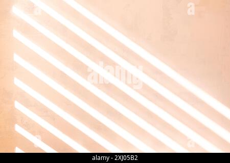 Sonnenlicht durch eine Lattenrollos auf eine strukturierte gemalte Wand, pfirsichfarbener Hintergrund, UK Stockfoto