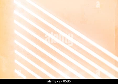 Sonnenlicht durch eine Lattenrollos auf eine strukturierte gemalte Wand, pfirsichfarbener Hintergrund, UK Stockfoto