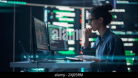 Weibliche Entwicklerinnen denken und tippen am Computer, umgeben von großen Bildschirmen, die Coding Language zeigen. Fokussierter Programmierer, Der Software Erstellt Und Codierungstests Durchführt. Futuristisches Programmierungskonzept Stockfoto