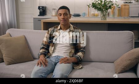 Porträt nach Hause froh gute Stimmung positive Ethnicity Mann lächelnd Blick in die Kamera ruhend Wochenende auf der bequemen Couch gesunder afroamerikanischer ethnischer Mann Stockfoto