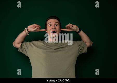 Ein Mann verzerrt sein Gesicht mit seinen Händen, was einen lustigen oder dramatischen Ausdruck erzeugt. Seine Hände sind in der Nähe seiner Augen, seines Mundes und seiner Wangen positioniert Stockfoto