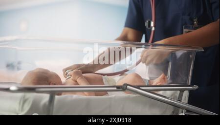 Entbindungskrankenhaus Station: Freundliche schwarze Kopfschwester verwendet Stethoskop, um Herzschlag und Lungen des erholenden Neugeborenen Baby im Bett zu hören. Afrikanischer Kinderarzt führt die Untersuchung im Kindergarten durch Stockfoto