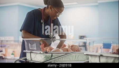 Professionelle afrikanische Krankenschwester beruhigen ein entzückendes kleines kaukasisches Neugeborenes Kind in der Kinderklinik. Medizinisches Gesundheitswesen, Entbindungskrankenhaus und Elternschaftskonzept Stockfoto
