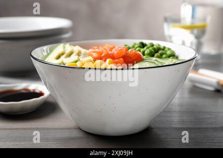 Leckerer Salat mit Lachs und Gemüse auf Holztisch, Nahaufnahme Stockfoto