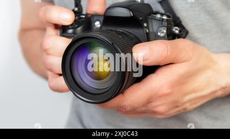 Nahaufnahme einer Person, die ein Kameraobjektiv anpasst, während sie eine Digitalkamera hält. Stockfoto