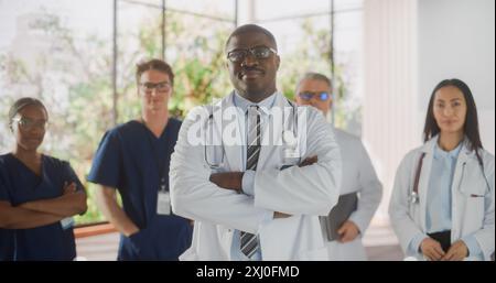 Team Porträt einer Frau und eines Mannes erfolgreich verschiedene medizinische Fachkräfte, die als Gruppe in einem modernen Krankenhausbüro stehen. Afroamerikaner Doktor steht näher an der Kamera Stockfoto