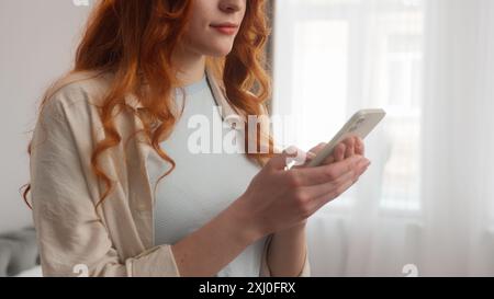 Sorglose Kaukasische Frau Frau Frau Frau Lächeln Typ Nachricht Touchscreen Smartphone Handy zu Hause. Entspanntes Mädchen 20s Model chatten online Social Stockfoto