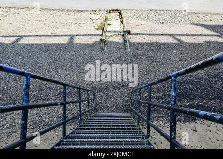 Metalltreppen hinunter zum steinigen Strand und ehemaligen Steg an der Themse bei Ebbe, London, England, Großbritannien Stockfoto