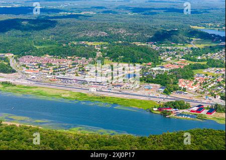 Ein Blick aus der Vogelperspektive auf ein Dorf in Schweden, eingebettet in üppiges Grün und angrenzend an ein großes Gewässer. Das Dorf verfügt über eine Mischung aus Wohnhäusern Stockfoto