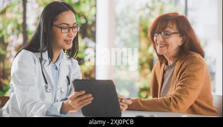 Ärztin zeigt einem Patienten mittleren Alters während der Konsultation in einer Gesundheitsklinik einen Tablet-Computer mit medizinischen Testergebnissen. Hausarzt sitzt hinter einem Schreibtisch im Krankenhausbüro Stockfoto