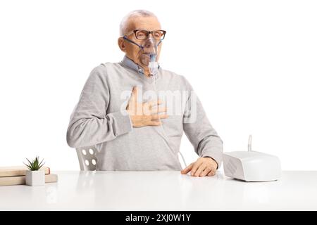 Älterer Mann mit Atemproblemen unter Verwendung eines Verneblers auf weißem Hintergrund Stockfoto