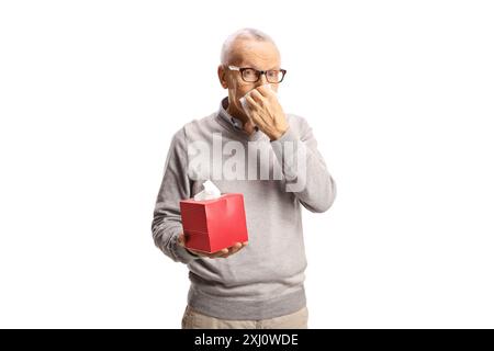 Älterer Mann, der die Nase bläst und eine Schachtel Papiertücher auf weißem Hintergrund hält Stockfoto