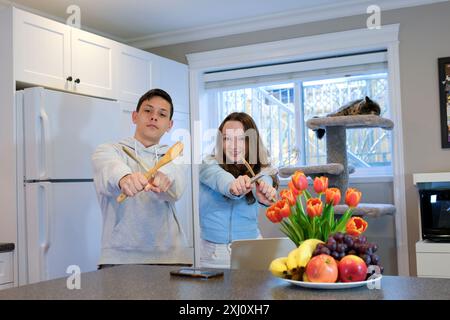 Paare, die in einer gemütlichen Küche tanzen und Hände halten, genießen Hobby und lustiges aktives Wochenende zusammen, Ehemann hob die Frau in Armen und Kreisen und drehte sie im Tanz. Die Familie feiert den Umzug in ein neues Zuhause Stockfoto