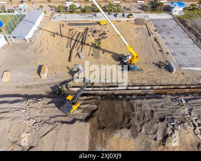 Bauarbeiten an der Küste. Schwere Maschinen arbeiten, um das Fundament vor Wasser und Sturmwellen zu stärken. Blick von der Drohne. Stockfoto