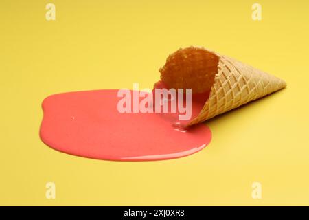 Geschmolzenes Eis und Waffelkegel auf gelbem Hintergrund Stockfoto