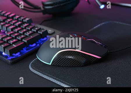 Computermaus, Mauspad und RGB-Tastatur auf schwarzem Hintergrund Stockfoto